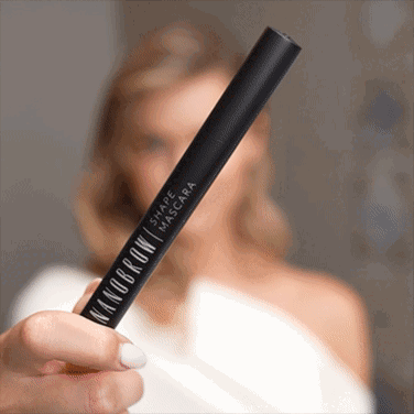 Una donna dagli occhi azzurri in un vestito bianco che applica la Shape Mascara